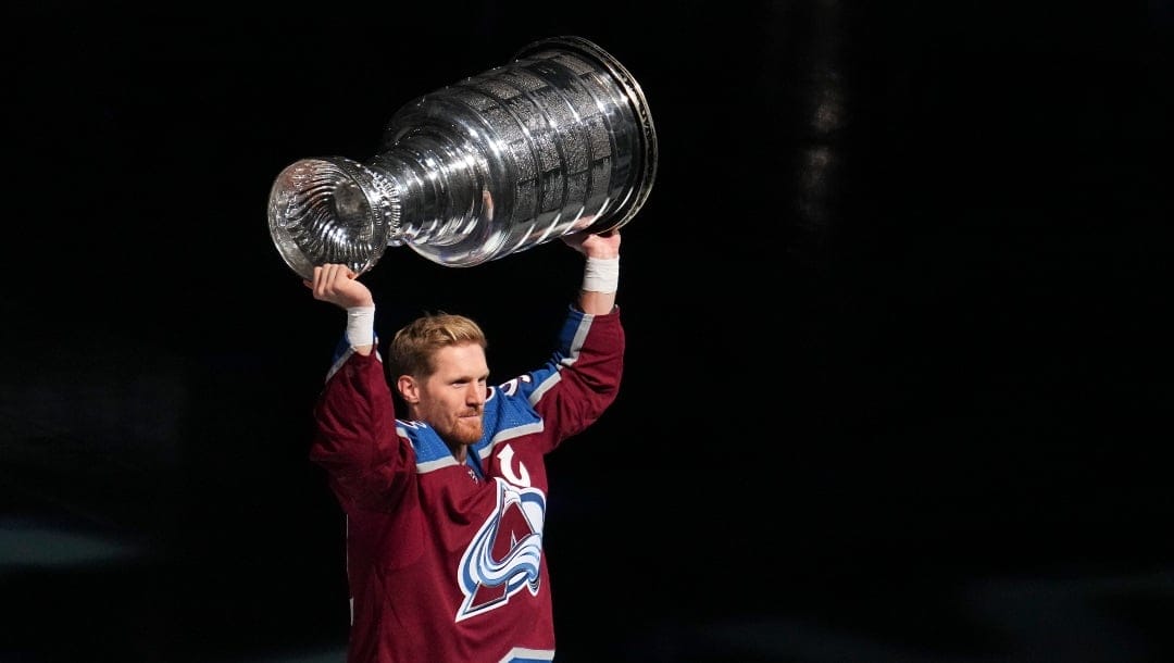 Colorado Avalanche left winger Gabriel Landeskog hoists the Stanley Cup for fans before the championship banner is lifted to the rafters during the an NHL hockey game against the Chicago Blackhawks Wednesday, Oct. 12, 2022, in Denver. (AP Photo/Jack Dempsey)