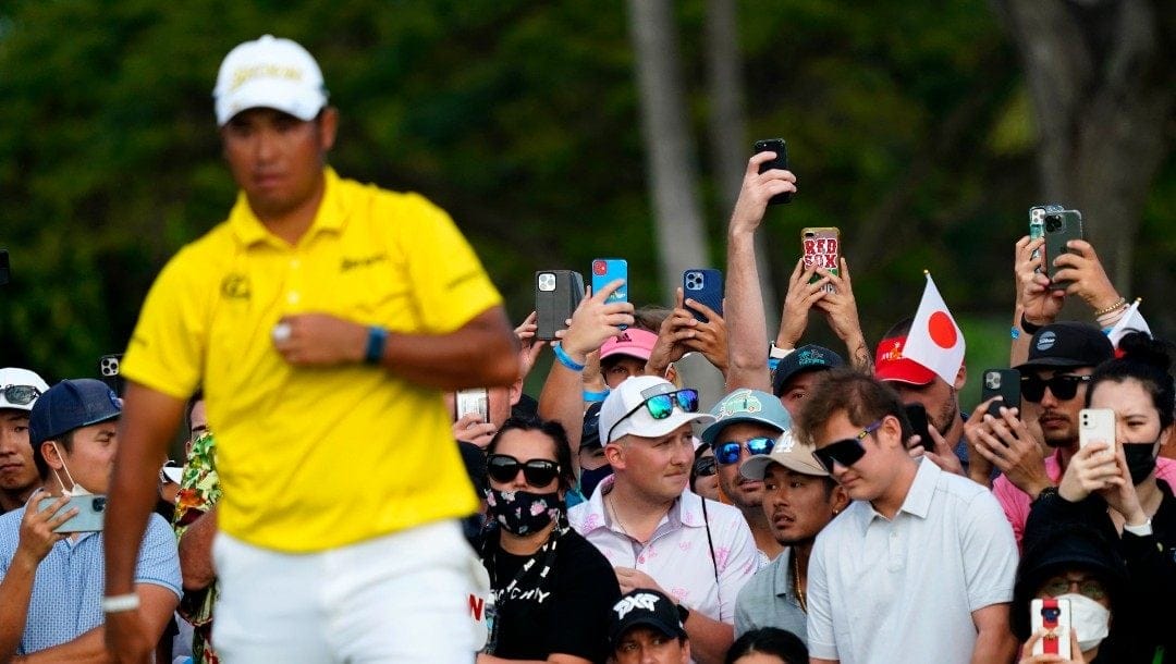 Fans take watch Hideki Matsuyama, of Japan, line up his shot on the 18th green during the final round of the Sony Open golf tournament, Sunday, Jan. 16, 2022, at Waialae Country Club in Honolulu.