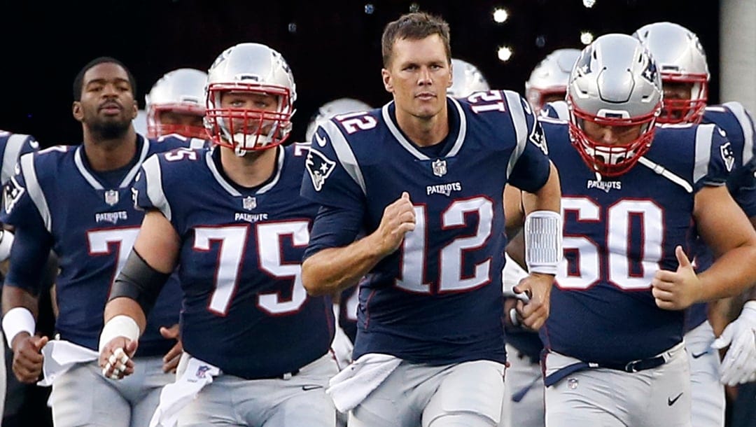 Then-New England Patriots quarterback Tom Brady (12) leads his team onto the field