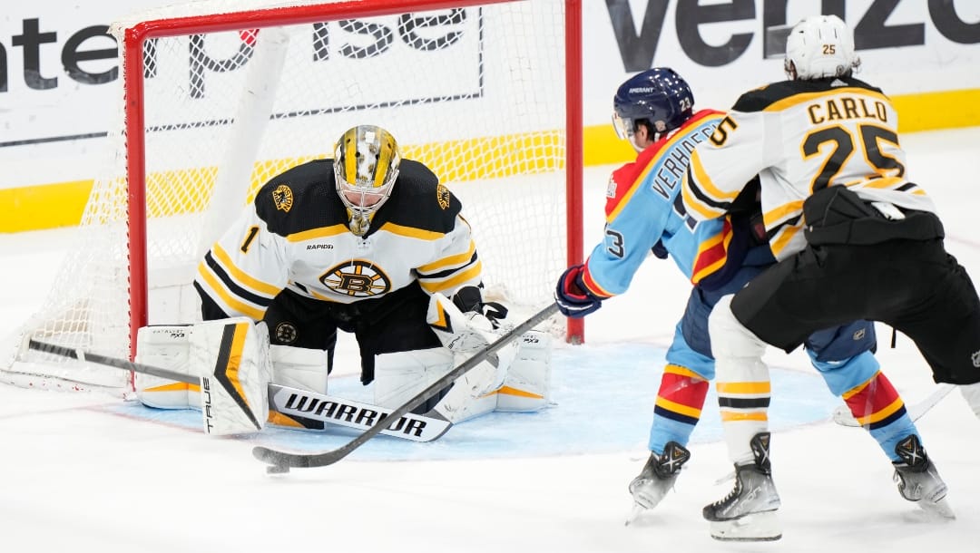 Florida Panthers center Carter Verhaeghe (23) attempts a shot at Boston Bruins goaltender Jeremy Swayman (1) as he skates with defenseman Brandon Carlo (25) during the third period of an NHL hockey game, Saturday, Jan. 28, 2023, in Sunrise, Fla. (AP Photo/Wilfredo Lee)