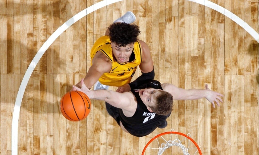 A shot from above of two opposing basketball players jumping for the ball in the air