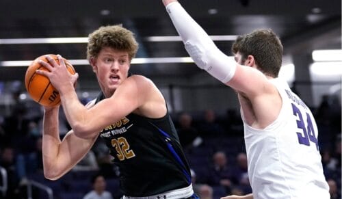 No 32 basketball player from Port Wayne trying to pass the NBA game ball while an opponent defends