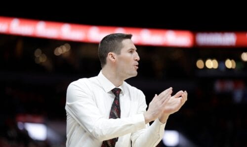 A team manager in a dress shirt and tie clapping his hands in encouragement