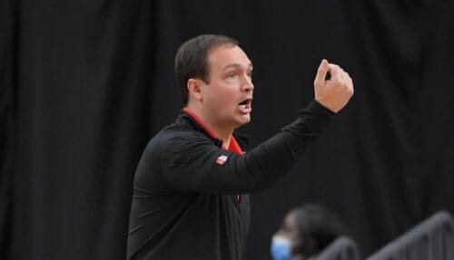 A coach dressed in a black tracksuit, signalling to players