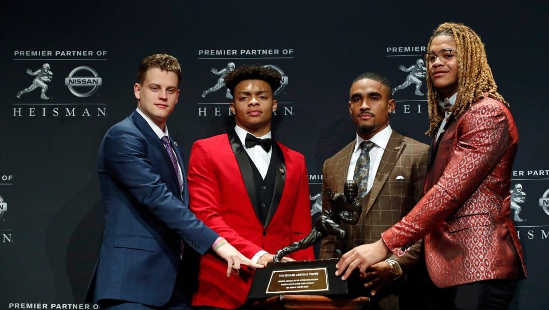 NCAA college football players and Heisman Trophy finalists, from left, LSU quarterback Joe Burrow, Ohio State quarterback Justin Fields, Oklahoma quarterback Jalen Hurts and Ohio State defensive end Chase Young pose for a photo with the Heisman Trophy, Saturday, Dec. 14, 2019, in New York. (AP Photo/Jason Szenes)