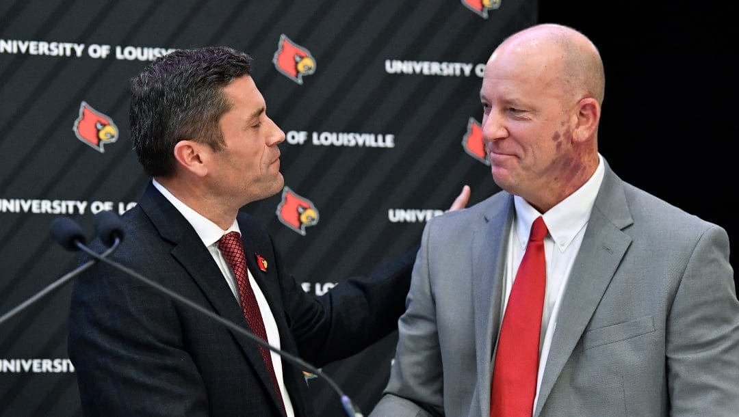 Louisville athletic director Josh Heird, left, shakes hands with newly named football coach Jeff Brohm in Louisville, Ky., Thursday, Dec. 8, 2022. (AP Photo/Timothy D. Easley)