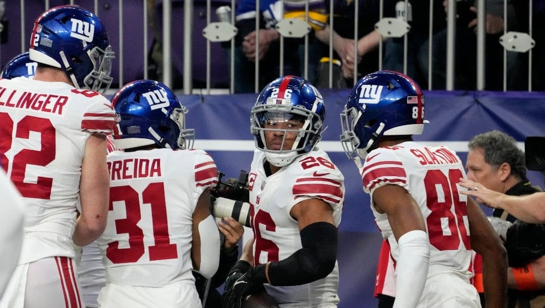 New York Giants running back Saquon Barkley (26) celebrates with teammates after scoring a touchdown during the first half of an NFL wild card playoff football game against the Minnesota Vikings, Sunday, Jan. 15, 2023, in Minneapolis. (AP Photo/Charlie Neibergall)