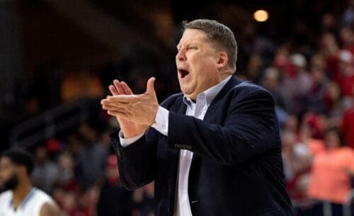 A team manager wearing a suit, enthusiastically clapping his hands