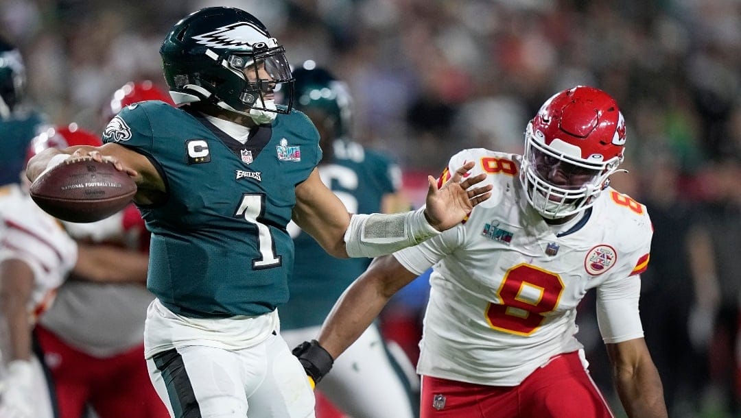 Philadelphia Eagles quarterback Jalen Hurts (1) passes under pressure by Kansas City Chiefs defensive end Carlos Dunlap (8) during the second half of the NFL Super Bowl 57 football game, Sunday, Feb. 12, 2023, in Glendale, Ariz. (AP Photo/Brynn Anderson)