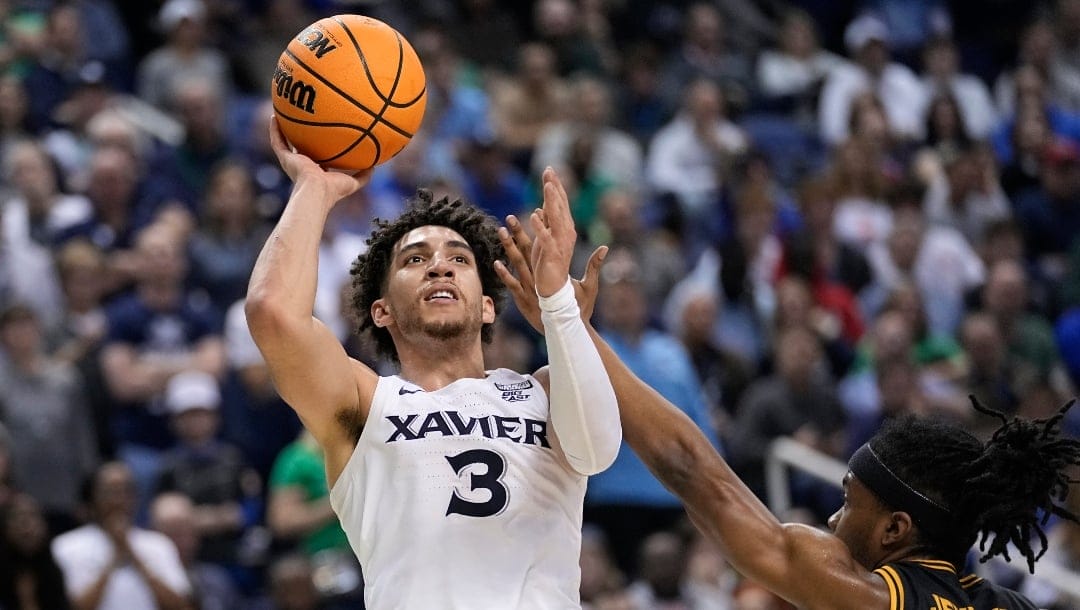 Xavier guard Colby Jones (3) shoots as Kennesaw State guard Kasen Jennings (13) defends during the first half of a first-round college basketball game in the NCAA Tournament on Friday, March 17, 2023, in Greensboro, N.C. (AP Photo/John Bazemore)