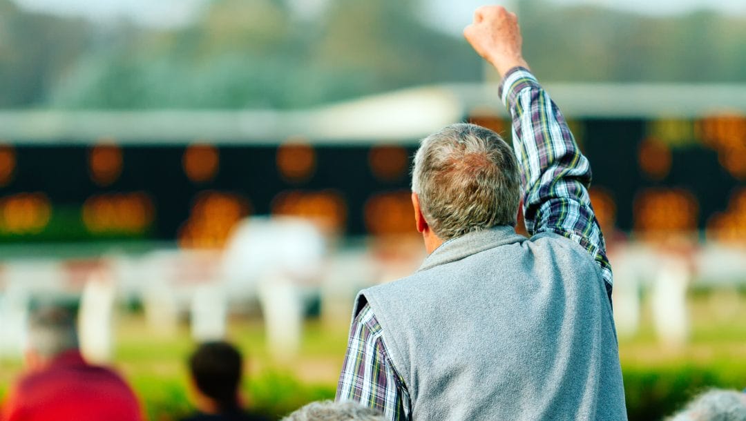 A bettor raises a fist to celebrate a victory at the racetrack.
