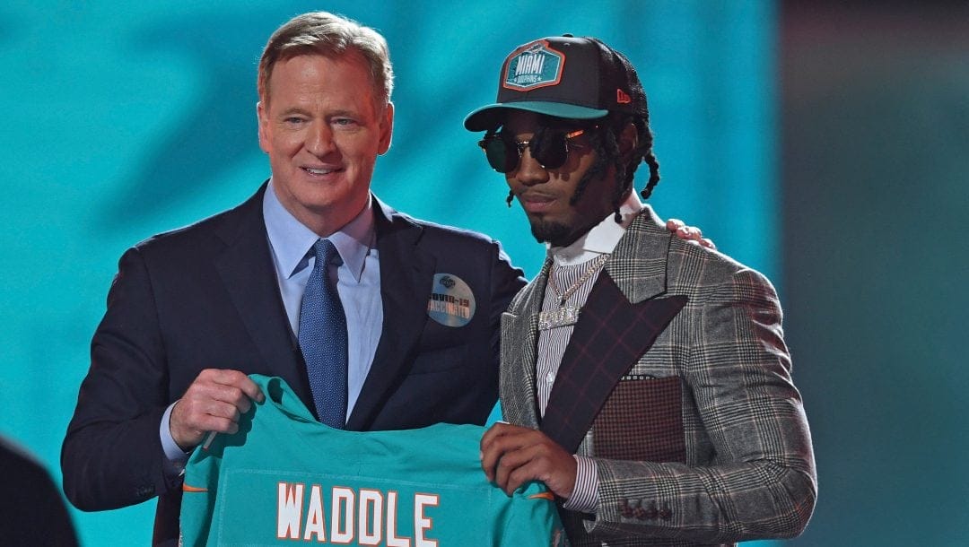 Alabama wide receiver Jaylen Waddle, right, holds a team jersey with NFL Commissioner Roger Goodell after he was chosen with sixth pick by the Miami Dolphins in the first round of the NFL football draft, Thursday, April 29, 2021, in Cleveland.