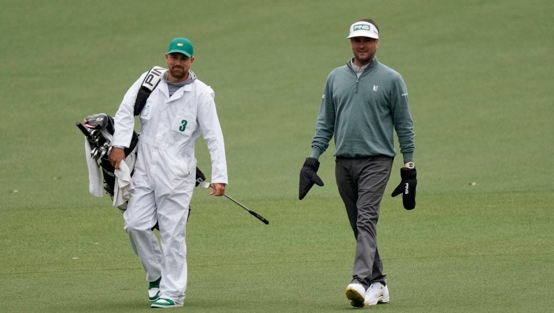 Bubba Watson wears mittens while walking down the second fairway with his caddie Gabriel Sauer during the third round at the Masters golf tournament on Saturday, April 9, 2022, in Augusta, Ga.