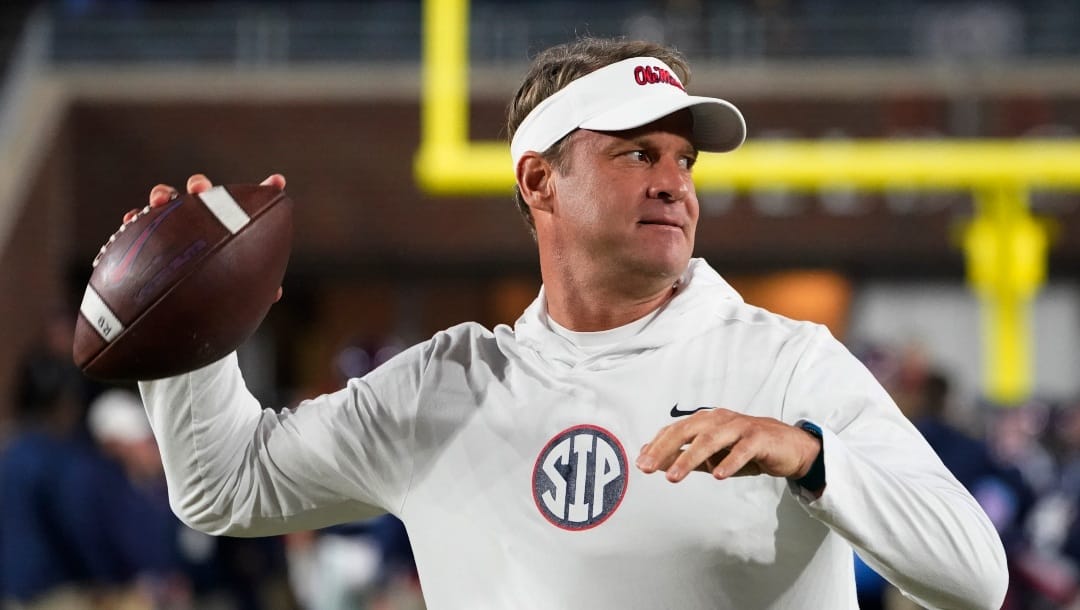 Mississippi coach Lane Kiffin passes the ball to a player during warmups for the team's NCAA college football game against Mississippi State in Oxford, Miss., Thursday, Nov. 24, 2022. (AP Photo/Rogelio V. Solis)