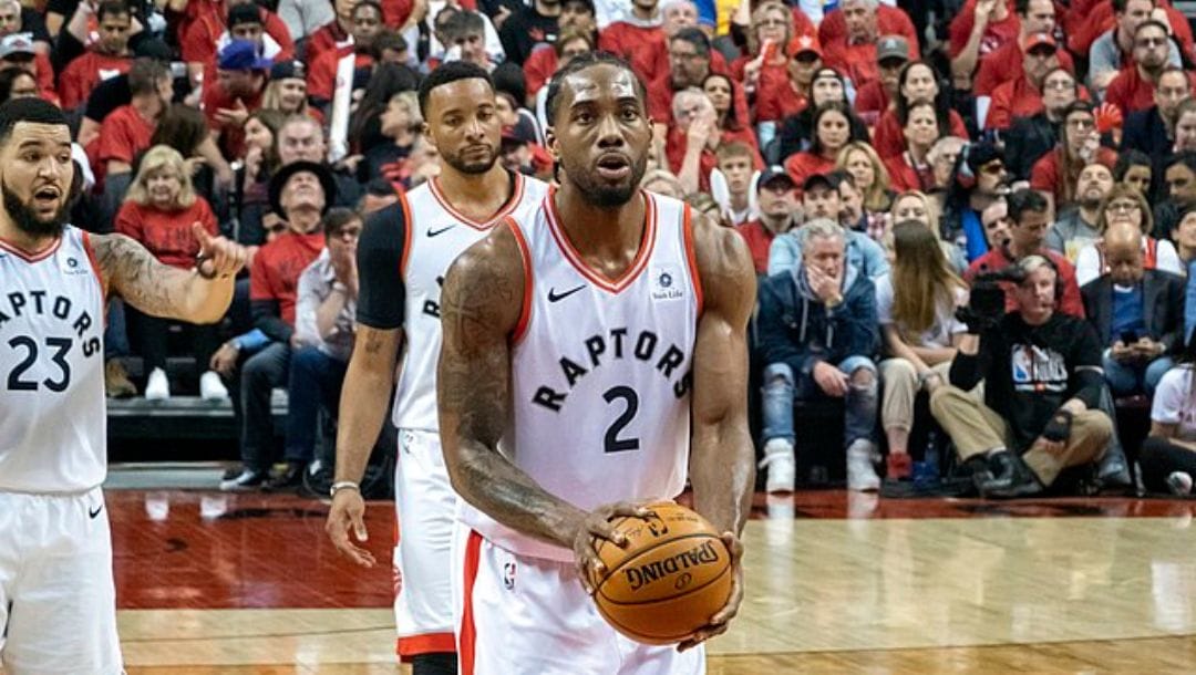 Kawhi Leonard shooting a free throw at Game 2 of the 2019 NBA Finals, with teammates Norman Powell and Fred VanVleet at the back.