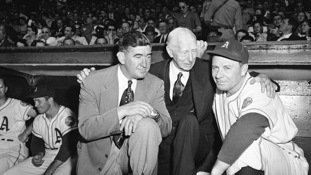 Mickey Cochrane, left, newly appointed general manager of the Philadelphia Athletics, stands in the dugout in street clothes in Philadelphia, May 27, 1950 with his boss, Connie Mack, and Jimmy Dykes, newly named assistant manager, just before the A's took the field to beat the New York Yanks, 60 to 1.