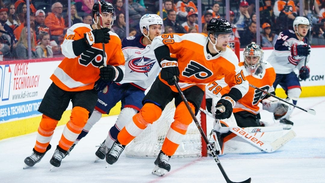 Philadelphia Flyers' Adam Ginning, front right, skates the puck up the ice as he goes past goalie Carter Hart, second from right, during the third period the team's NHL hockey game against the Columbus Blue Jackets, Tuesday, April 11, 2023, in Philadelphia. The Flyers won 4-3 in overtime.