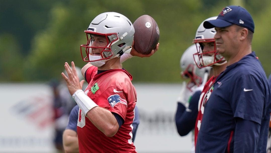 New England Patriots quarterback Mac Jones, left, winds up to pass in front of offensive coordinator Bill O'Brien, right, during an NFL football team practice, Tuesday, June 13, 2023, in Foxborough, Mass.