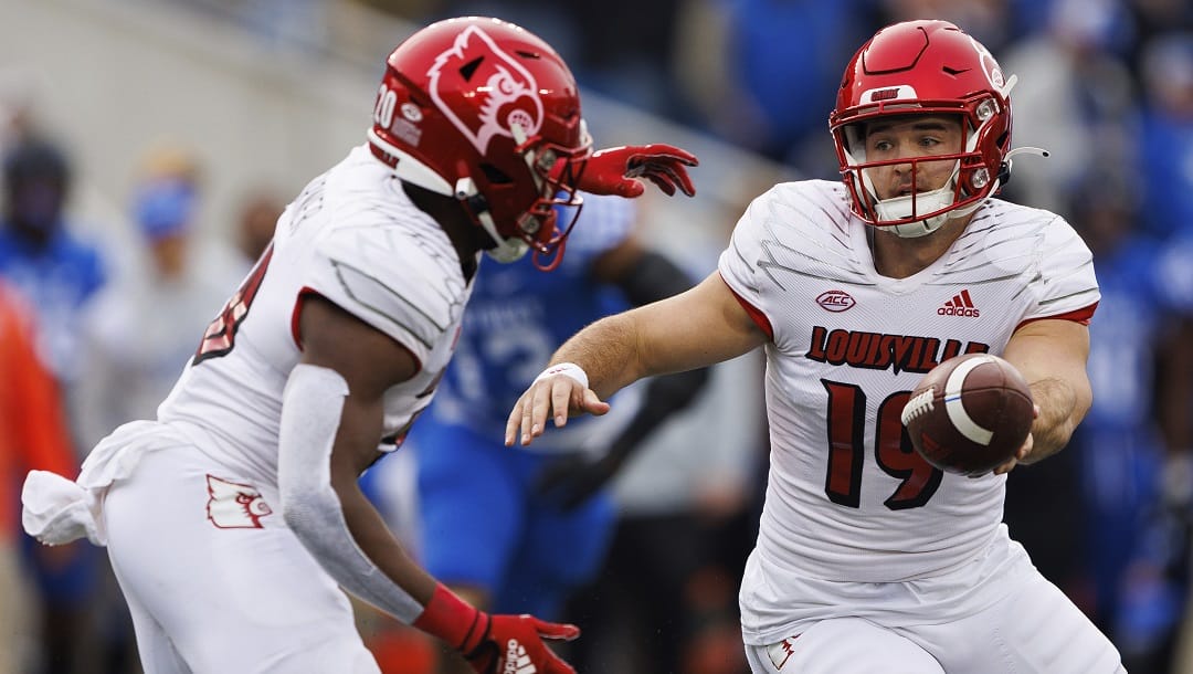 Louisville quarterback Brock Domann (19) hands the ball off to Louisville running back Maurice Turner (20) during the first half of an NCAA college football game against Kentucky in Lexington, Ky., Saturday, Nov. 26, 2022.