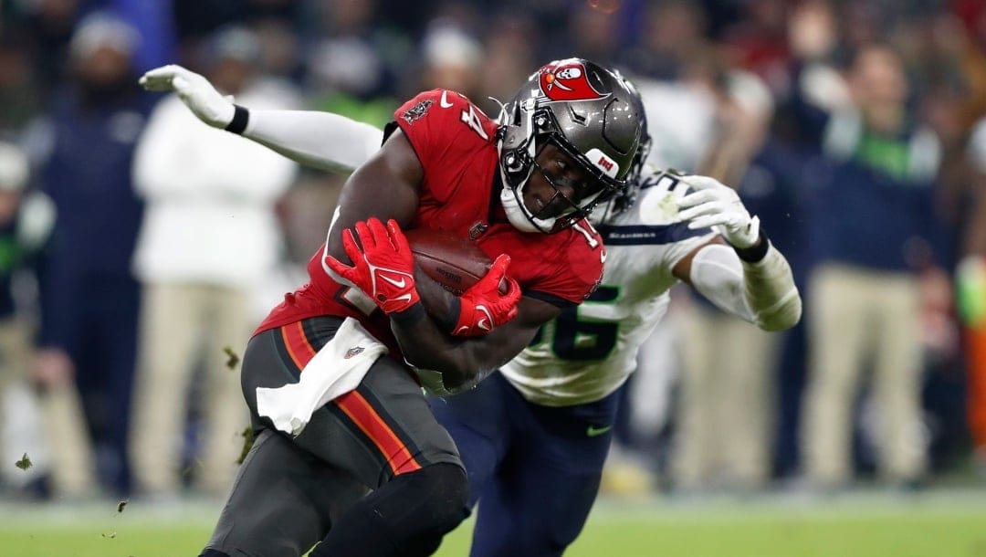 Tampa Bay Buccaneers wide receiver Chris Godwin (14) looks to run the ball past Seattle Seahawks linebacker Jordyn Brooks (56) during an NFL football game at Allianz Arena in Munich, Germany, Sunday, Nov. 13, 2022. The Tampa Bay Buccaneers defeated the Seattle Seahawks 21-16. (AP Photo/Steve Luciano)