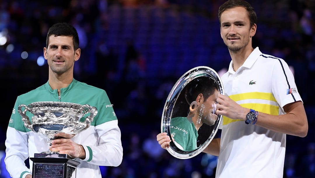 Serbia's Novak Djokovic, left, holds the Norman Brookes Challenge Cup after defeating Russia's Daniil Medvedev, right, in the men's singles final at the Australian Open tennis championship in Melbourne, Australia, Sunday, Feb. 21, 2021.