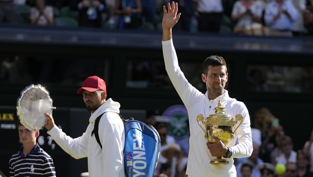 Serbia's Novak Djokovic, right, holds the winners trophy as he celebrates after beating Australia's Nick Kyrgios, left, to win the final of the men's singles on day fourteen of the Wimbledon tennis championships in London, Sunday, July 10, 2022.
