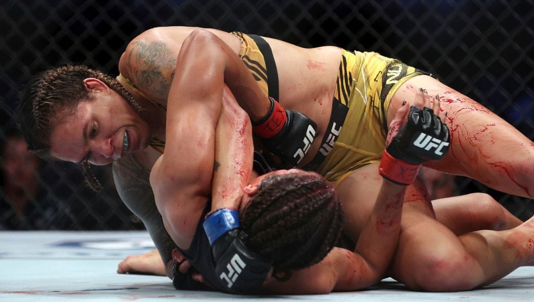 Amanda Nunes (top) battles Julianna Pena on the ground in a mixed martial arts women's bantamweight title bout at UFC 277.