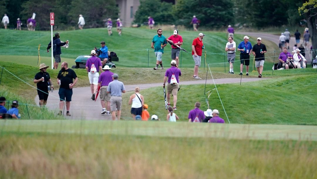 Fans and tournament staff make their way off the course after play was suspended due to inclement weather during the third round of the 3M Open golf tournament at the Tournament Players Club in Blaine, Minn., Saturday, July 23, 2022.