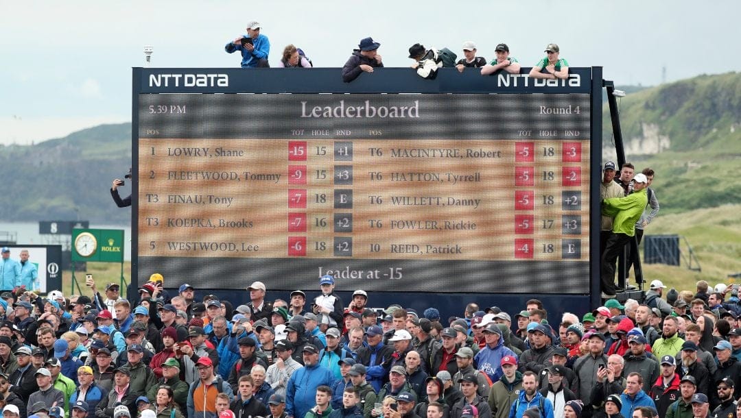 Spectators clamber on to and on top of a scoreboard as they vie to get a glimpse of Ireland's Shane Lowry and England's Tommy Fleetwood as they play during the final round of the British Open Golf Championships at Royal Portrush in Northern Ireland, Sunday, July 21, 2019.