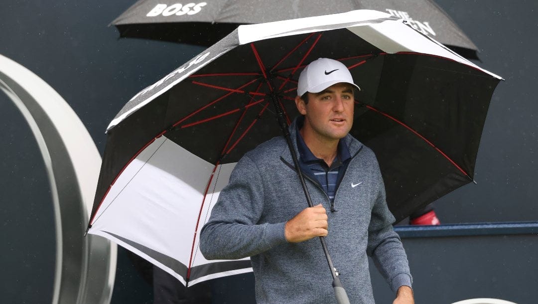 United States' Scottie Scheffler waits under an umbrella on the 1st tee as light rain falls during a practice round for the British Open Golf Championships at the Royal Liverpool Golf Club in Hoylake, England, Tuesday, July 18, 2023. The Open starts Thursday, July 20.