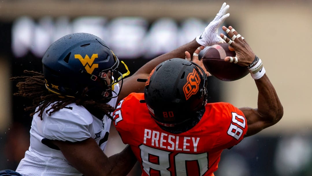 Oklahoma State wide receiver Brennan Presley (80) catches a ball as West Virginia defensive back Aubrey Burks (2) try to block it during the first half of the NCAA college football game in Stillwater, Okla., Saturday Nov. 26, 2022. (AP Photo/Mitch Alcala)