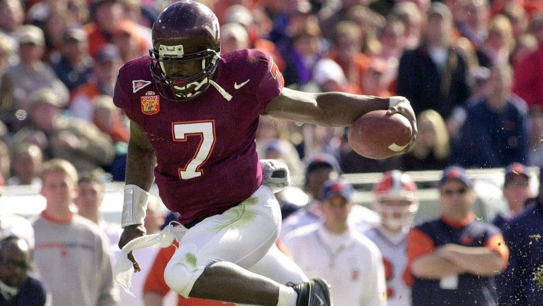 In this Jan. 1, 2001, file photo, Virginia Tech quarterback Michael Vick (7) eludes Clemson's Keith Adams for a short gain in the first quarter of the Gator Bowl NCAA college football game in Jacksonville, Fla. Public opposition is growing against the planned induction of former football star Michael Vick into the Virginia Tech Sports Hall of Fame. The Roanoke Times reported that two online petitions at change.org had received more than 90,000 combined signatures against the September induction.