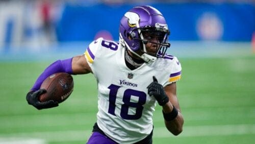 Vikings player number 18 running with a NFL ball game in hand.