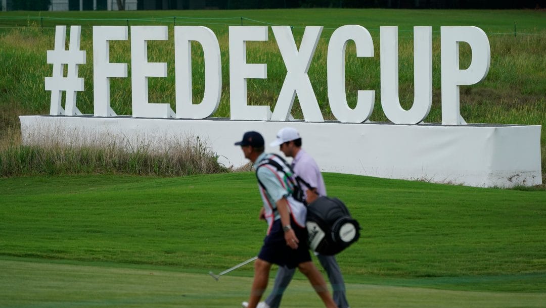 A golfer walks past a FedEx Cup sign along the 13th fairway during the first round of the St. Jude Championship golf tournament Thursday, Aug. 11, 2022, in Memphis, Tenn.