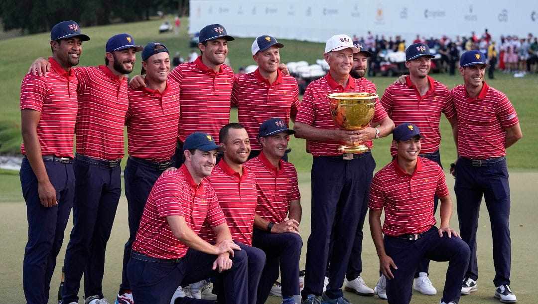 USA team captain Davis Love III, white hat, and his team pose for a photo with the Presidents Cup trophy after defeating the International team in match play at the Presidents Cup golf tournament at the Quail Hollow Club, Sunday, Sept. 25, 2022, in Charlotte, N.C.