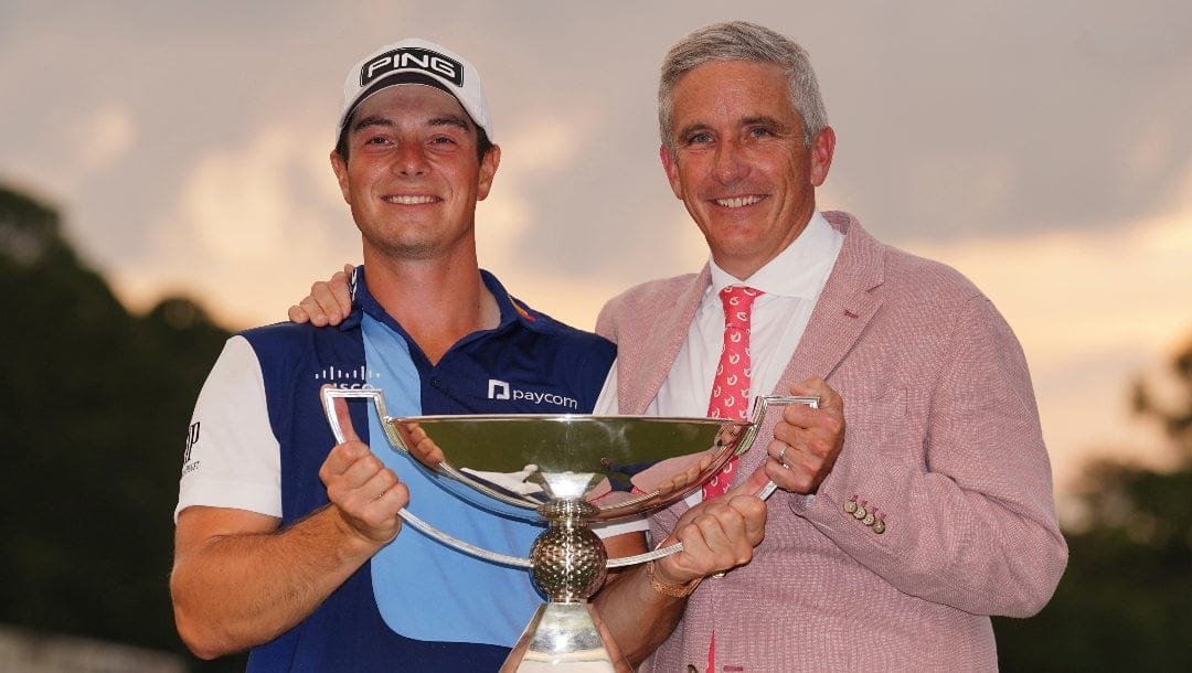 Viktor Hovland, of Norway, left, celebrates winning the Tour Championship golf tournament with the FedEx Cup trophy with Jay Monahan, commissioner of the PGA, on the 18th green, Sunday, Aug. 27, 2023, in Atlanta.