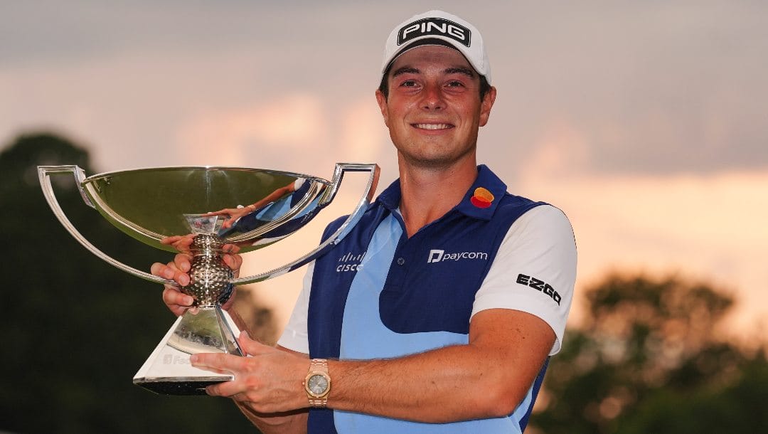 Viktor Hovland, of Norway, celebrates winning the Tour Championship golf tournament with the FedEx Cup trophy on the 18th green, Sunday, Aug. 27, 2023, in Atlanta.