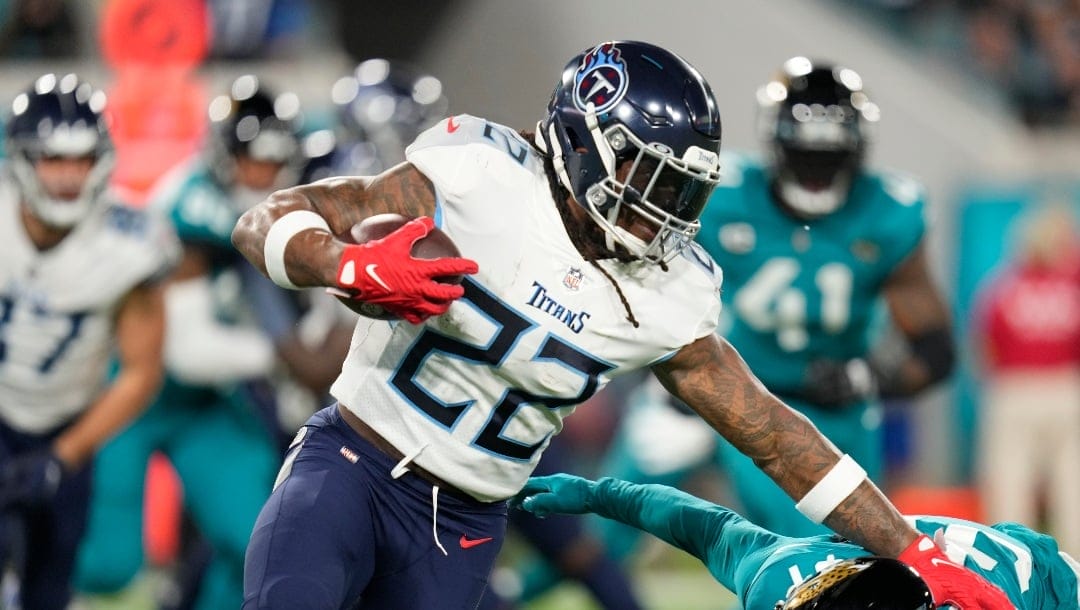 Tennessee Titans running back Derrick Henry (22) carries against Jacksonville Jaguars cornerback Darious Williams (31) in the first half of an NFL football game, Saturday, Jan. 7, 2023, in Jacksonville, Fla. (AP Photo/John Raoux)