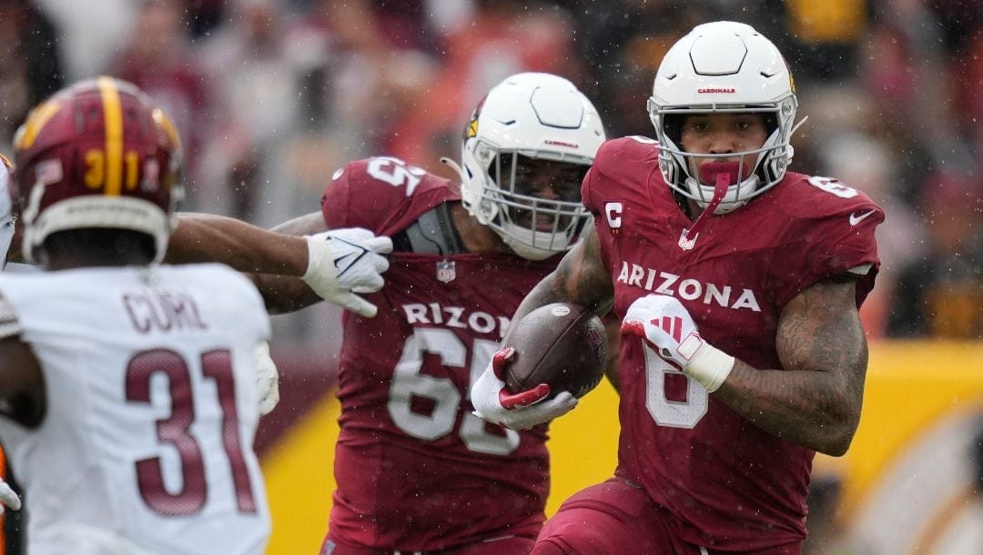 Arizona Cardinals running back James Conner (6) runs with the ball as Washington Commanders safety Kamren Curl (31) and Arizona Cardinals offensive tackle Elijah Wilkinson (65) move in during the second half of an NFL football game, Sunday, Sept. 10, 2023, in Landover, Md.