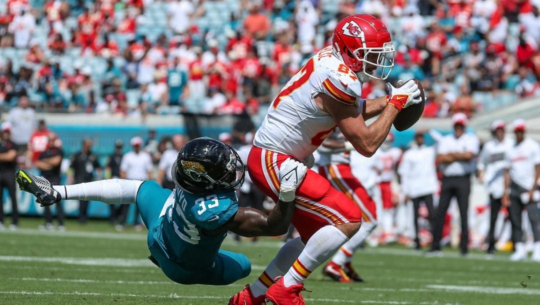 Kansas City Chiefs tight end Travis Kelce (87) catches a pass while defended by Jacksonville Jaguars linebacker Devin Lloyd (33), left, in action during the second half of an NFL football game, Sunday, Sept. 17, 2023, in Jacksonville, Fla. The Chiefs defeated the Jaguars 17-9.