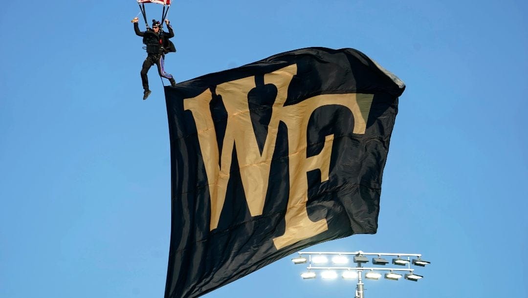 A parachutist brings a Wake Forest banner into the stadium before an NCAA college football game in Winston-Salem, N.C., Thursday, Aug. 31, 2023.
