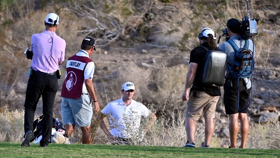 Patrick Cantlay, center, reviews his shot from the desert area off the 18th fairway during the final round of the Shriners Children's Open golf tournament, Sunday, Oct. 9, 2022, in Las Vegas.