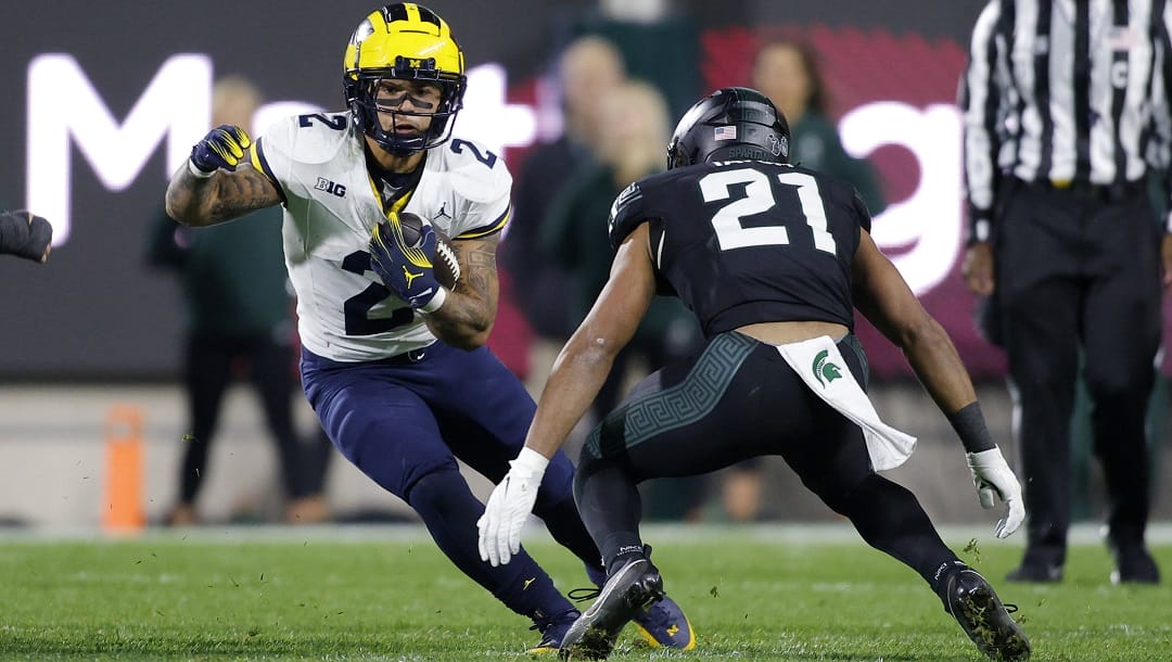 Michigan running back Blake Corum, left, runs against Michigan State defensive back Dillon Tatum (21) during an NCAA college football game, Saturday, Oct. 21, 2023, in East Lansing, Mich.