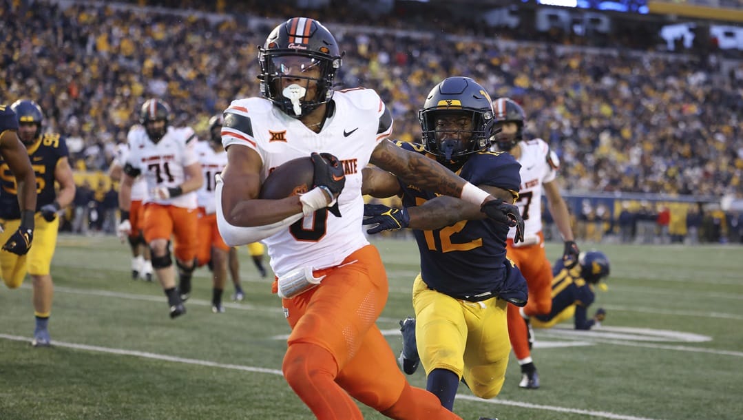 Oklahoma State's Ollie Gordon (0) carries the ball in for a rushing touchdown as West Virginia's Anthony Wilson (12) pursues during the second half of an NCAA college football game Saturday, Oct. 21, 2023, in Morgantown, W.Va.