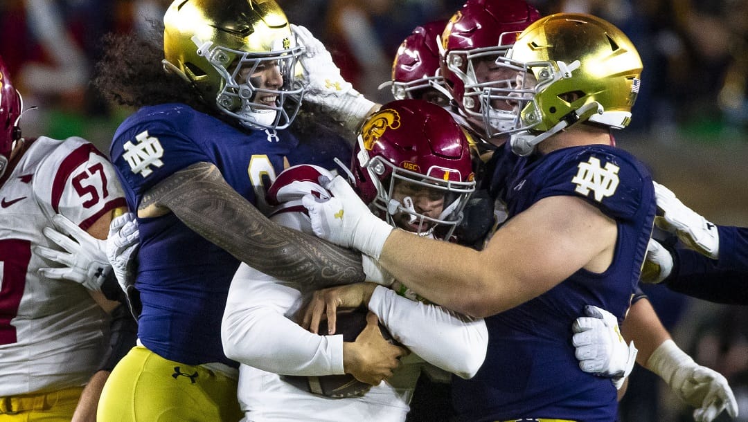 Notre Dame linebacker Marist Liufau, left, and Notre Dame defensive lineman Rylie Mills (99) wrap up Southern California quarterback Caleb Williams (13) during the second half of an NCAA college football game, Oct. 14, 2023, in South Bend, Ind.