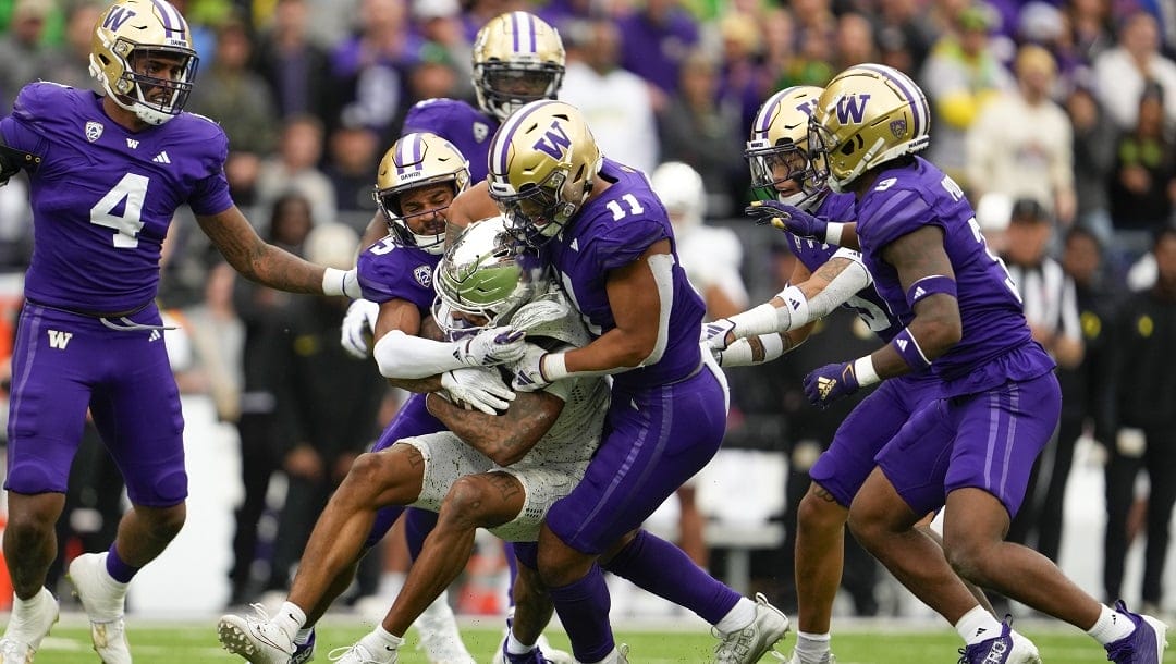 Oregon wide receiver Troy Franklin (11) is tackled by Washington cornerback Elijah Jackson and linebacker Alphonzo Tuputala (11) during the second half of an NCAA college football game, Saturday, Oct. 14, 2023, in Seattle. Washington won 36-33.