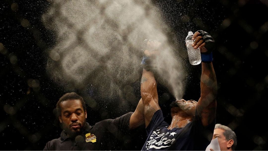 Bobby Green, right, spits out water as he has his arm raised in victory by referee Herb Dean after beating Josh Thomson.
