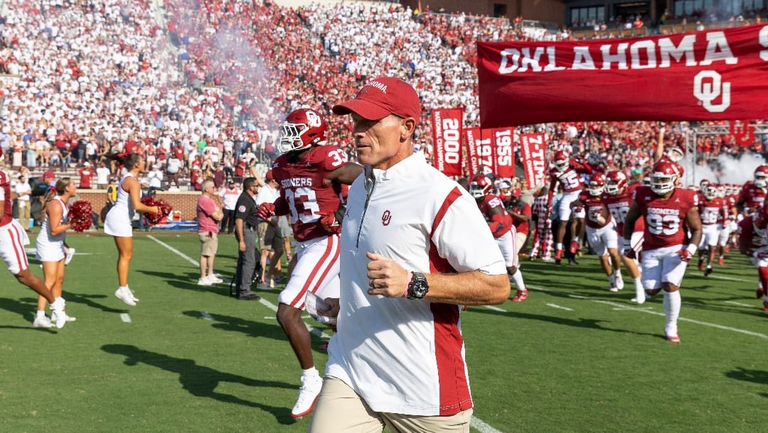 Oklahoma coach Brent Venables and players run onto the field before an NCAA college football game against SMU, Saturday, Sept. 9, 2023, in Norman, Okla. (AP Photo/Alonzo Adams)