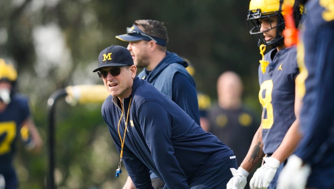 Michigan head coach Jim Harbaugh, left, watches during NCAA college football practice Friday, Dec. 29, 2023, in Carson, Calif. Michigan is scheduled to play against Alabama on New Year's Day in the Rose Bowl, a semifinal in the College Football Playoff. (AP Photo/Ryan Sun)