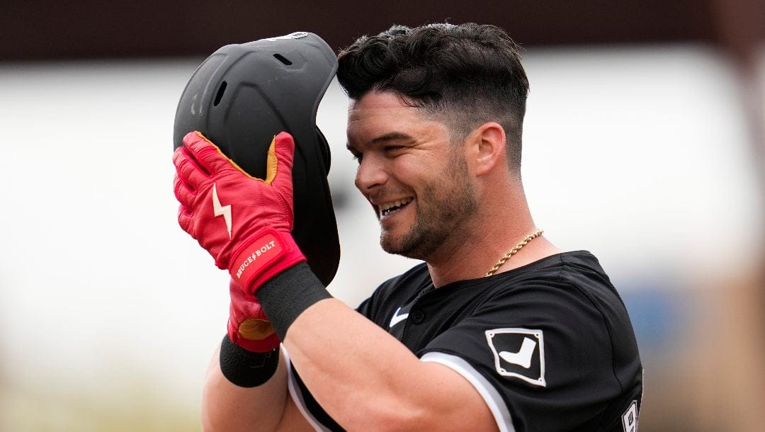 Chicago White Sox's Andrew Benintendi adjusts his helmet while standing on third base during the first inning of a spring training baseball game against the Texas Rangers in Phoenix, Monday, Feb. 26, 2024.